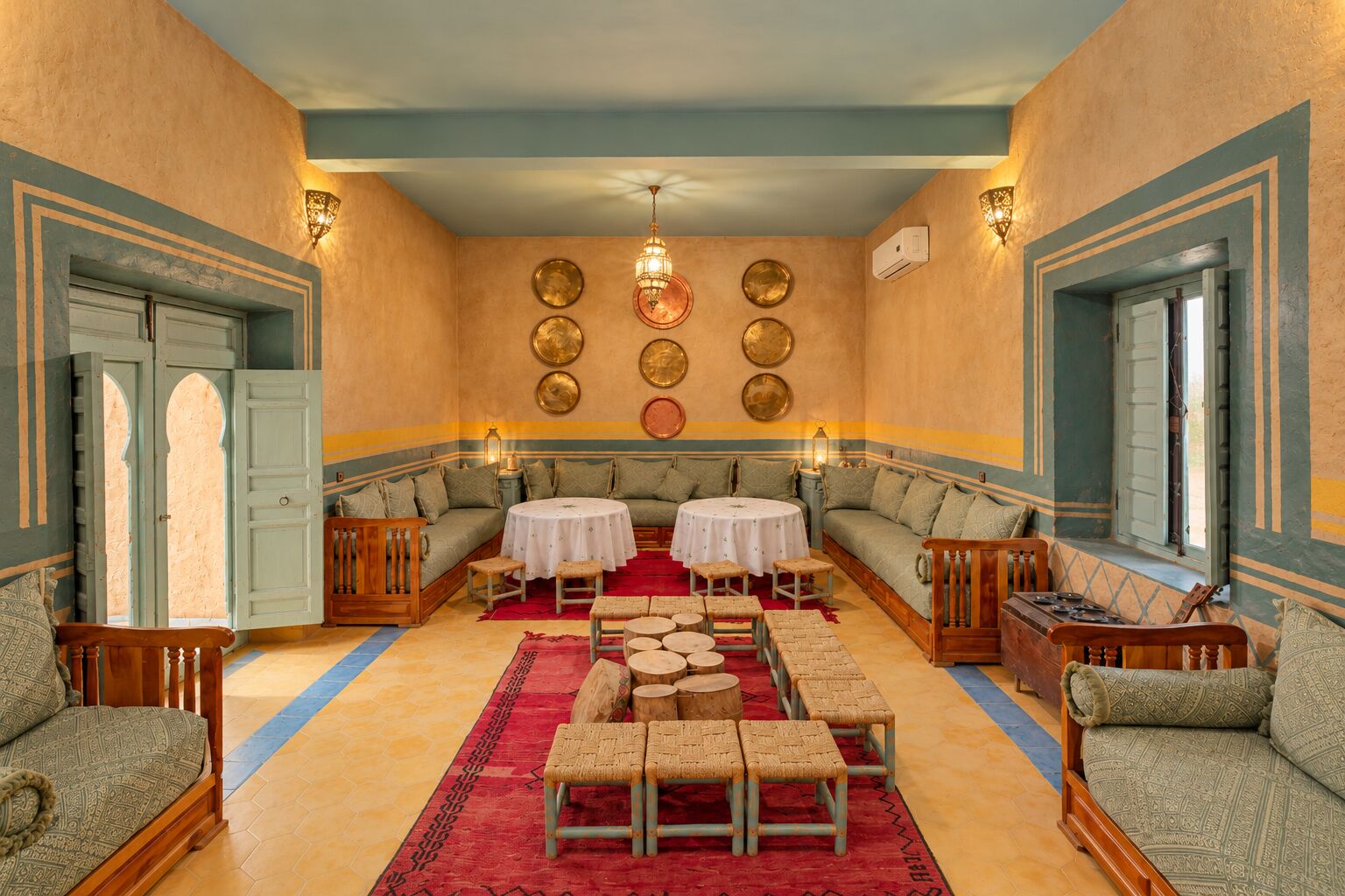 Moroccan lounge with low sofas and brass plates at Dar el Janoub, Merzouga