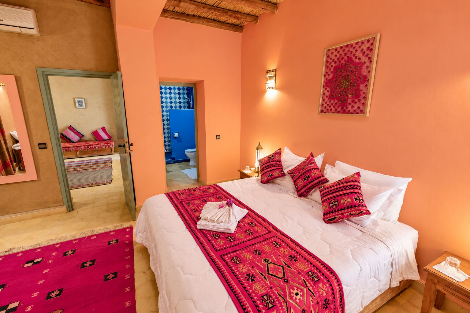 Double bedroom with red Moroccan textiles at Dar el Janoub, Merzouga