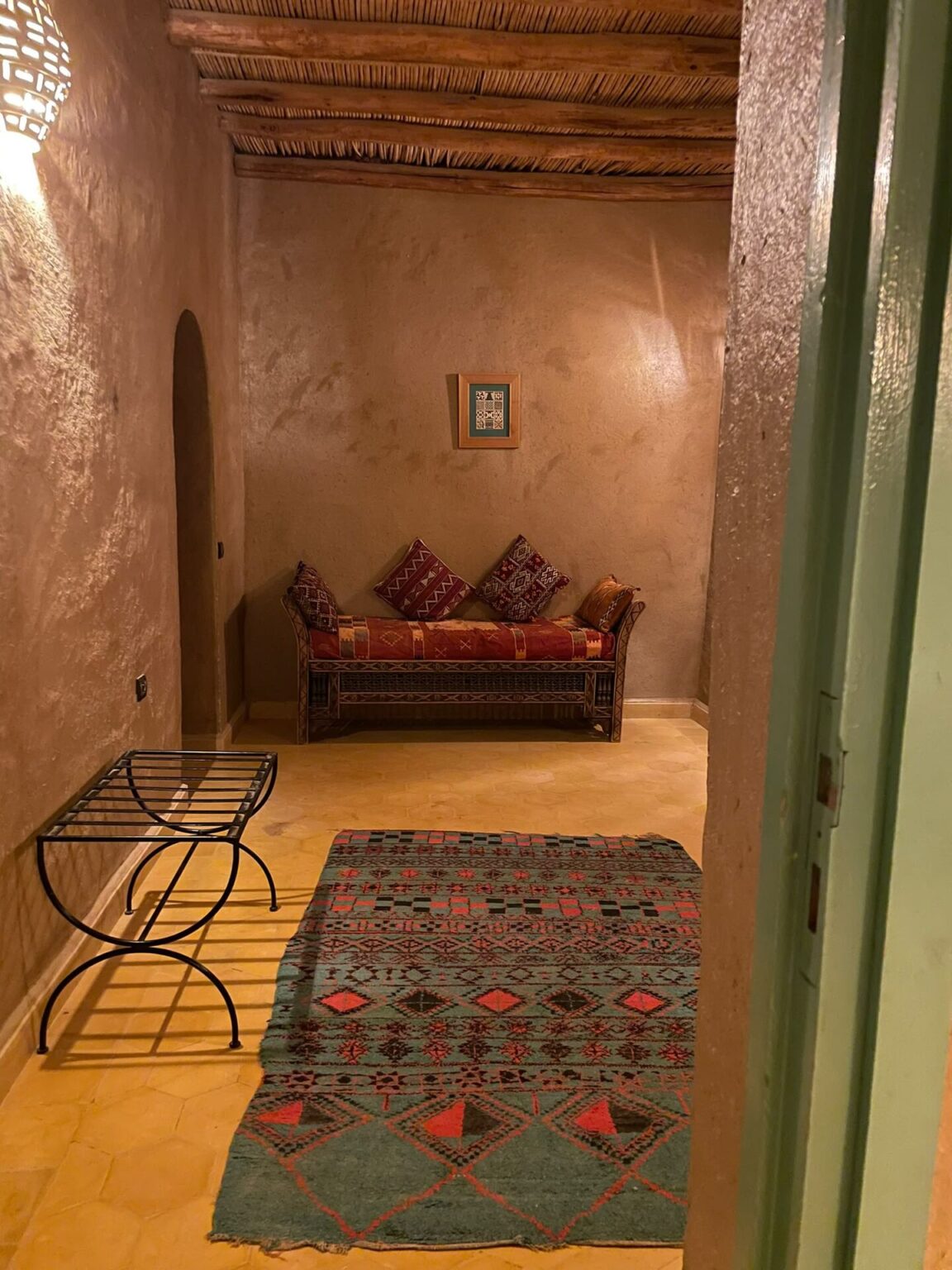 Guest room sitting area with red bench and Berber rug at Dar el Janoub